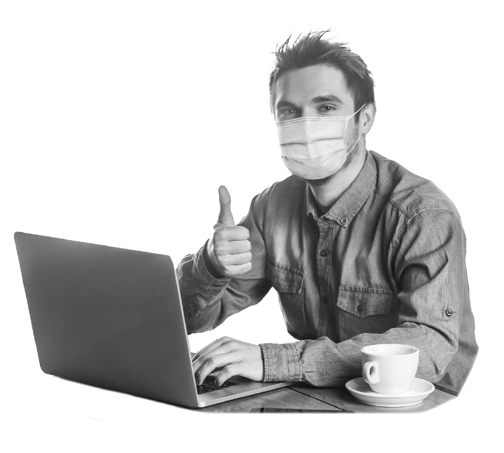 Masked man sitting at laptop giving thumbs up.