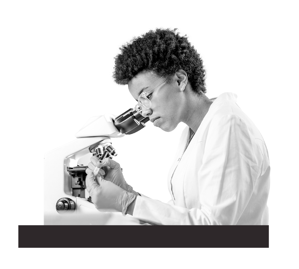 Black woman researcher writing on vial next to microscope.